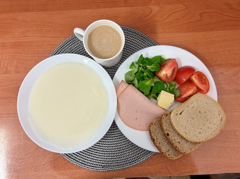 Na zdjęciu: Kasza manna na mleku, Kawa zbożowa z mlekiem, Chleb mieszany pszenno-żytni, Chleb Graham, Masło extra 82%, Filet zapiekany drobiowy, Pomidor, Roszponka